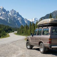 An SUV with a rooftop cargo box parked at a mountain highway pullout in the Canadian Rockies